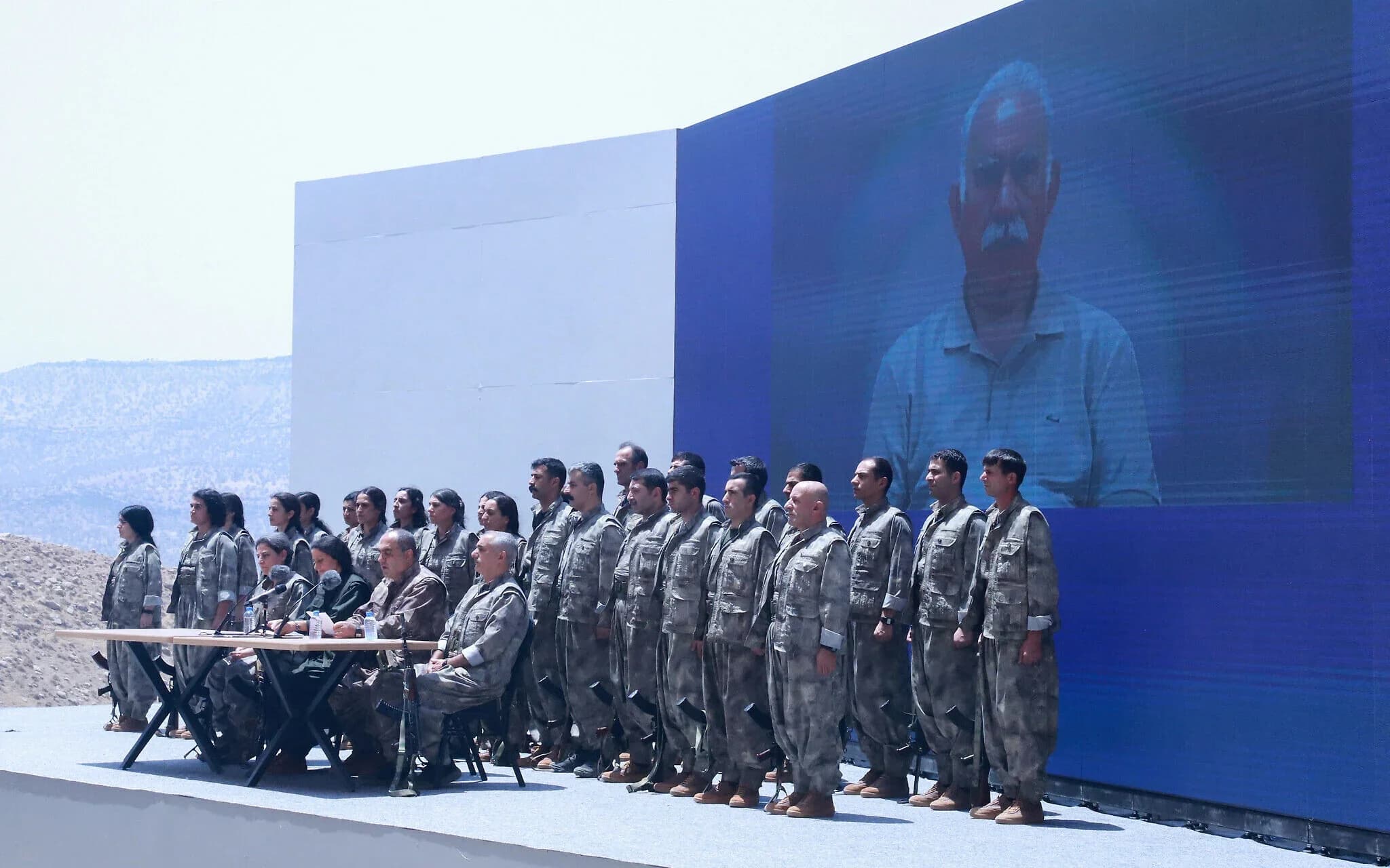 Kurdistan Workers’ Party (PKK) commanders and fighters stand in front of a picture of jailed PKK leader and founder Abdullah Ocalan during a disarmament ceremony in Sulaimani, July 11, 2025. Photo: AFP