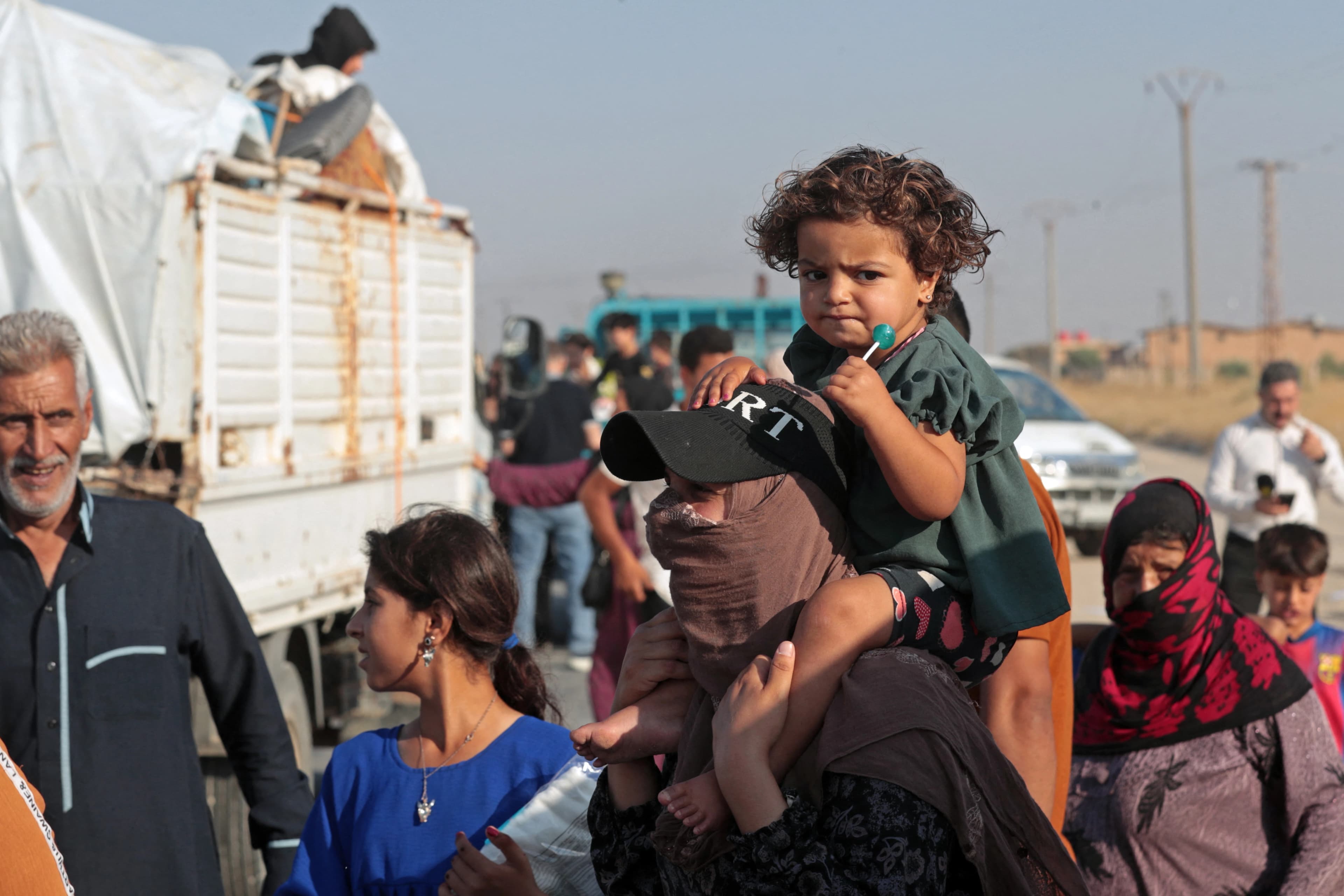 ژنێک لە کاتی گەڕانەوەی بۆ سەرێکانی منداڵەکەی لە کۆڵ کردووە. وێنە: AFP
